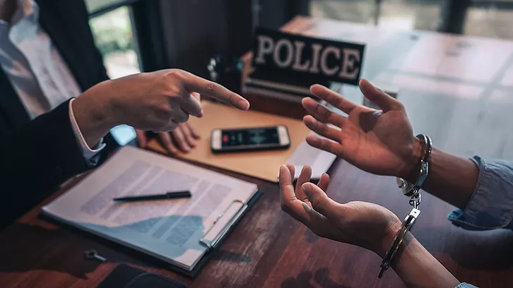 image of handcuffed person being interviewed by the police