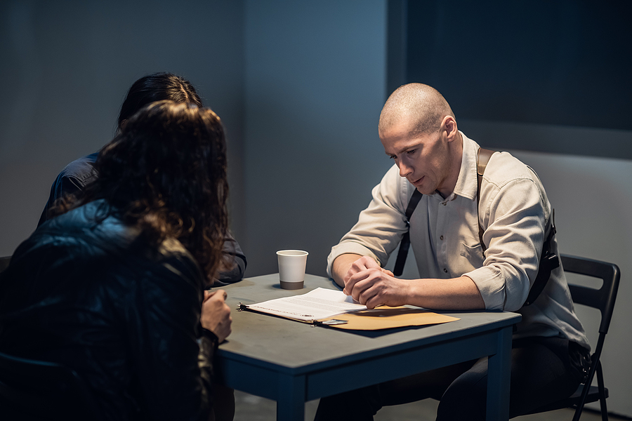 In The Interrogation Room, The Investigator And The Officer Are talking