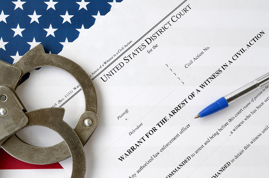 Police Search Without a Warrant , District court warrant for the arrest of a witness in a civil action papers with handcuffs and blue pen on United States flag. Permission to witness arrest